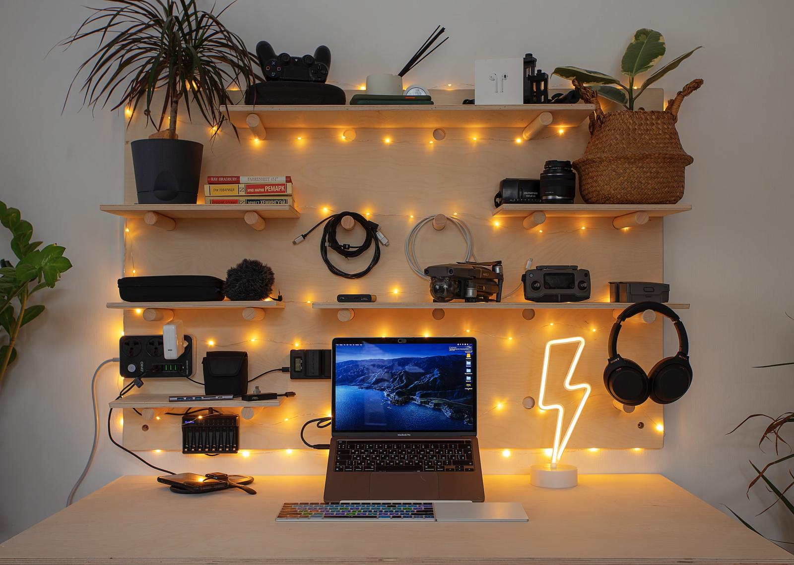 Homeoffice-Arbeitsplatz mit Laptop, Regalen, Pflanzen und Lichterkette